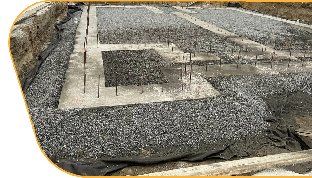 Préparation de fondation avec semelles de béton et lit de pierre compactée